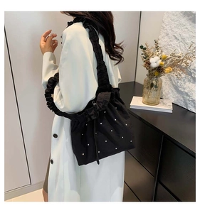 Close-up of black drawstring tote bag with stud detailing and ruched shoulder strap
