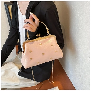 Dettaglio borsa rosa con chiusura a scatto, borchie a cuore e manico in metallo