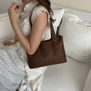 Brown leather vintage square tote bag with rivets and shoulder strap on a model