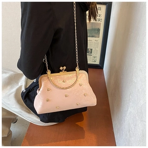 Borsa rosa vintage con borchie a cuore dorate e tracolla indossata da una modella
