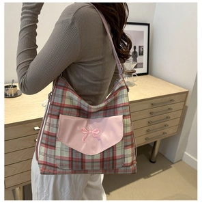 Detail of plaid canvas tote with pink leather bow pocket and adjustable strap for women
