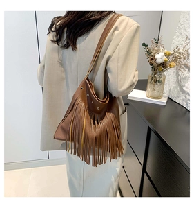 Detail of dark brown fringed shoulder bag featuring premium pebbled leather and long tassels