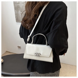 Detail of white crocodile-embossed leather bag with silver metal handle and logo lock