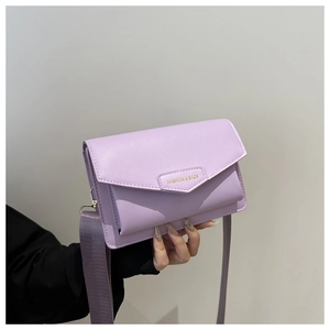 Close-up of lavender leather crossbody bag featuring wide fabric strap and gold fashion logo