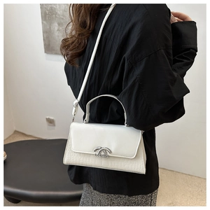 Detail of white square crossbody bag with crocodile texture and silver metal buckle
