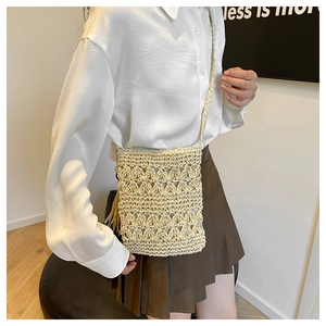Detail of off-white crochet crossbody bag featuring floral lace texture and long tassels