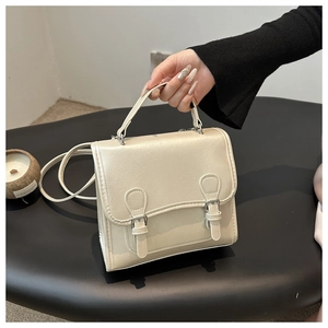 Detail of cream pleated shoulder bag with metallic silver buckles and sleek handle
