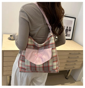 Detail of red and green plaid tote with pink bow embroidery and leather strap