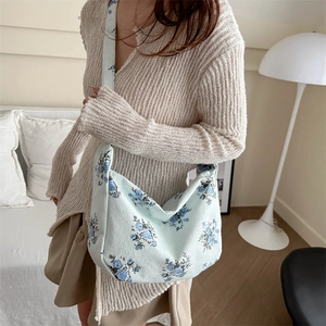 Sac bandoulière en velours côtelé bleu clair à fleurs porté par un mannequin
