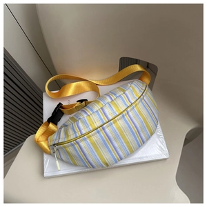Détail du sac banane rayé avec bandoulière en nylon jaune posé sur une chaise blanche