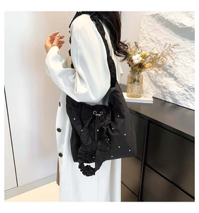 Detailed view of black pleated tote bag with silver polka dots and drawstring buckle