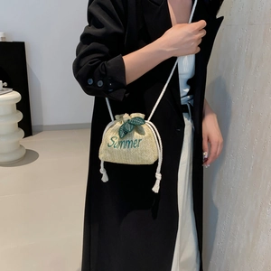 Summer straw bucket bag with green embroidery and leaf detail worn with chic outfit