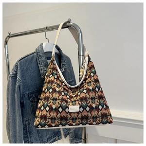 Detail of colorful geometric woven tote bag with white leather trim and fashion label
