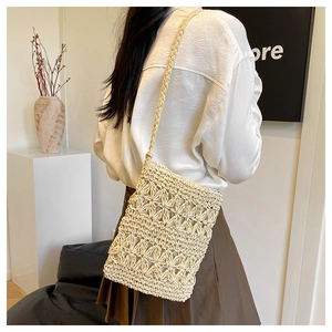 Close-up of bohemian hollow-out woven straw bag with hand-knitted strap on a model