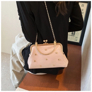 Dettaglio borsa in pelle rosa con borchie a cuore e tracolla a catena dorata lucida