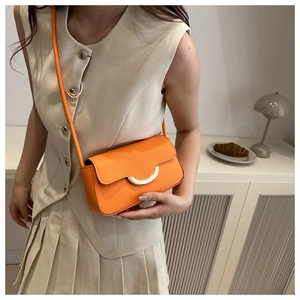 Détail d'un sac bandoulière orange vif avec une boucle élégante en forme de demi-lune