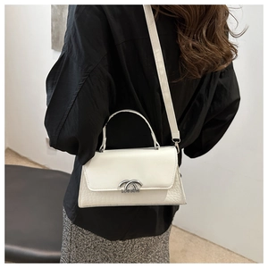 Detail view of the silver double C metal lock on a white embossed leather crossbody bag