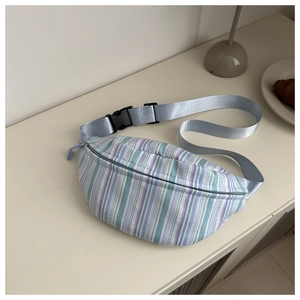 Détail du sac banane à rayures colorées avec sangle réglable et boucle sur table