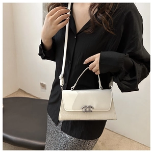 Detail of white leather handbag with faux crocodile texture and silver metal buckle