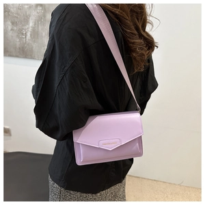 Close-up of lavender crossbody flap bag with wide woven strap and fashion lettering