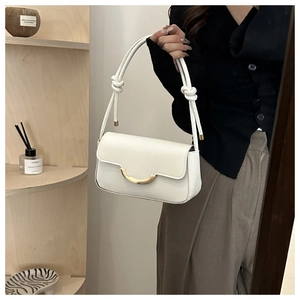 Détail du sac à rabat blanc avec boucle dorée en demi-lune et bandoulière nouée