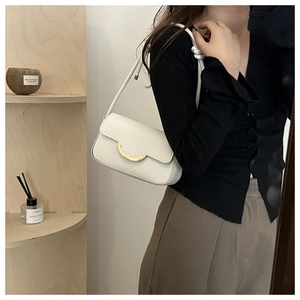 Detail of white minimalist shoulder bag with golden crescent buckle and knot strap detail