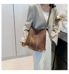 Brown leather tote bag with long fringe details shown on model in a minimalist setting