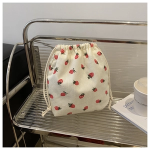 Détail d'un pochon en velours côtelé crème avec motif fraise et cordon de serrage