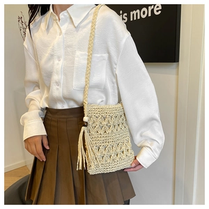 Detail of cream woven crossbody bag with bohemian tassels and hollow crochet patterns