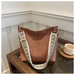 Detail of reddish-brown woven bucket bag with bohemian geometric jacquard shoulder strap