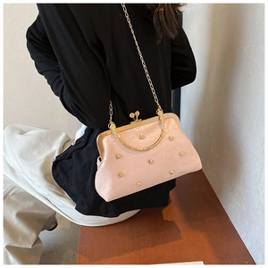 Borsa rosa a conchiglia con borchie a cuore e catena dorata su panca in legno