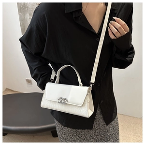 Detail of white crocodile pattern crossbody bag with silver twist lock on model