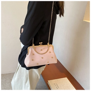 Dettaglio borsa rosa perlato con cuori decorativi e tracolla a catena dorata