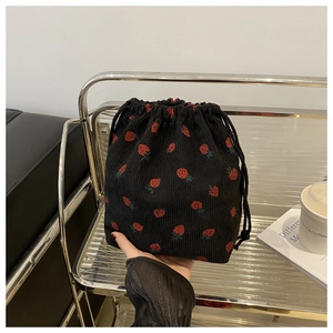 Détail du sac seau noir en velours côtelé avec cordon de serrage et motif fraises