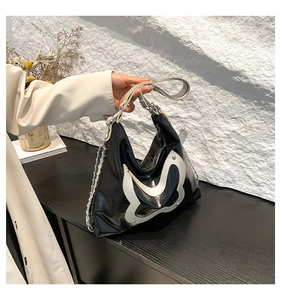 Detail der schwarzen Achseltasche aus Leder mit weißem Schmetterling und Metallnieten