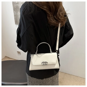 Detail view of white crocodile pattern leather crossbody bag with silver clasp and top handle