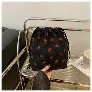 Détail du sac à cordon en velours noir avec imprimé fraises sur étagère métal