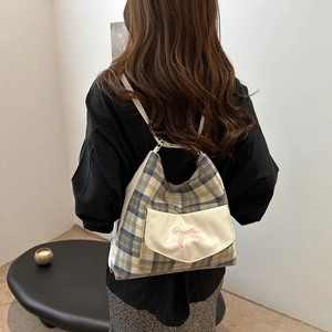 Fashionable plaid backpack with pink bow and cream leather trim worn by model