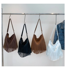 Detail showing four colors of bohemian fringe shoulder bags with studs on a display rack