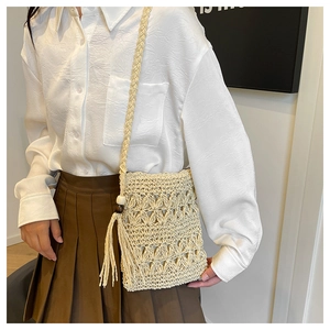 Detail of bohemian straw crossbody bag featuring intricate crochet and tassel accents