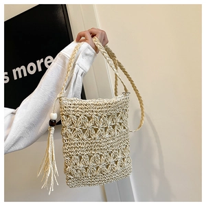 Detail of bohemian straw crossbody bag with floral weave, tassels and wooden beads