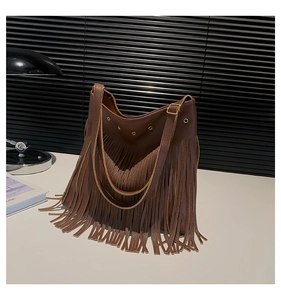 Close-up of deep brown bohemian tote bag showing leather fringe texture and metal grommets