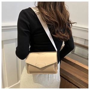 Detail of beige crossbody bag with wide fabric strap and metal fashion engraving
