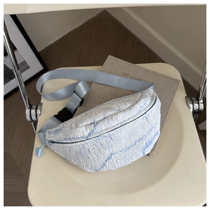 Macro detail of light blue textured puff crossbody bag with adjustable strap and buckle