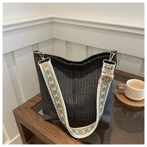 Detail of woven bucket bag with ethnic geometric wide shoulder strap and gold hardware
