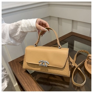Detail of khaki leather handbag with crocodile pattern base and silver metal lock