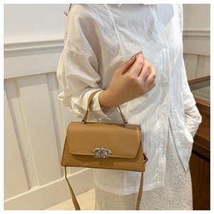 Detail of brown leather handbag with croc-embossed texture and silver metal buckle