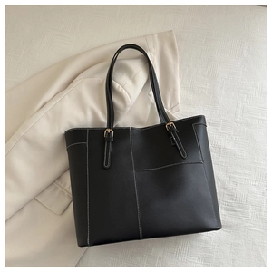 Détail du sac cabas noir avec coutures blanches contrastées et boucles en métal doré