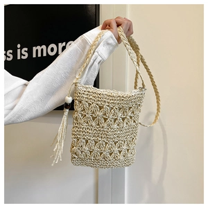 Detail of bohemian woven straw bag featuring floral hollow pattern and beaded tassel charm