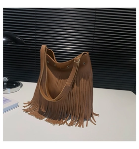 Close-up of caramel brown pebble leather tote bag with long bohemian tassel details